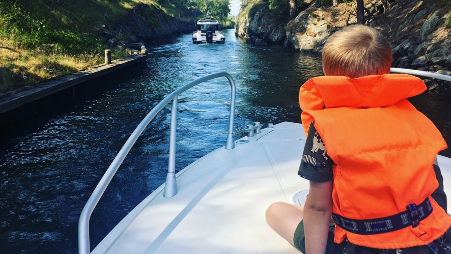 Pojke sitter i fören på en motorbåt som färdas genom Dragets kanal