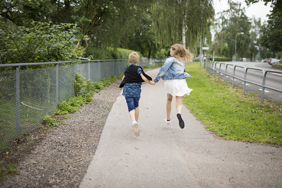 Två barn springer bortåt på en gångväg.