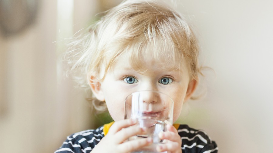 Barn dricker vatten i glas