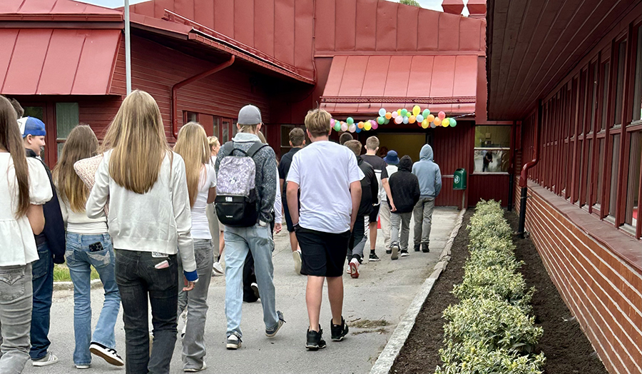Elever på väg in i en skola, som är dekorerad med ballonger.