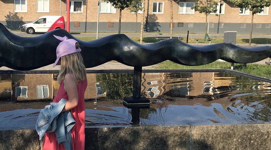 flicka vid skulptur med vatten