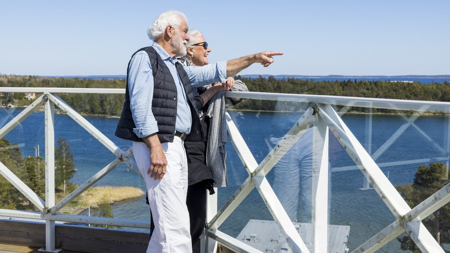 Äldre par pekar på utsikten över havet.