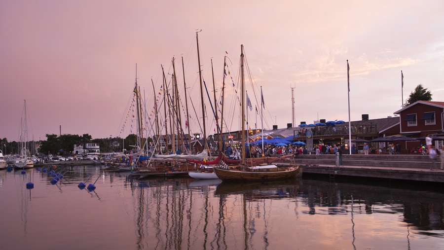 Gästhamn med segelbåtar och folkliv vid restaurang i solnedgång